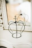 Wire crown with beaded ornaments in front of mirror on dressing table
