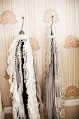 Scarves hanging from vintage coat hooks on wallpapered wall