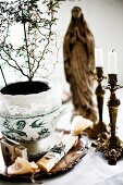 House plant in painted china pot and antique candlesticks in front of Madonna figurine