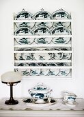 Painted decorative plates on wall rack above antique table lamp and china crockery on surface
