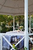 Round table with tablecloth and garden chairs in gazebo