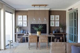 Wicker chairs at dining table below row of pendant lamps in front of brown-painted wall in rustic dining room