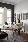 Frau an postmodernem, silberfarbenem Schreibtisch in elegantem Arbeitszimmer