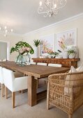 Wooden table, upholstered chairs and wicker armchair in dining room with South-Sea ambiance decorated with king protea