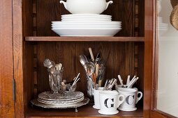 Mugs and other crockery in display case with open door