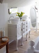 Vintage chest of drawers converted into washstand with twin countertop basins and cheval mirror in white bathroom