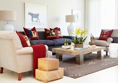 Rattan storage baskets next to upholstered furniture around rustic coffee table on rug in modern interior
