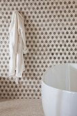 Gerundete Badewanne vor Wand mit wabenartigem Muster in Weiß- und Brauntönen