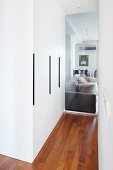 Einbauschrank im Gangbereich mit Glas Trennscheibe vor Wohnbereich und Blick auf Sofa