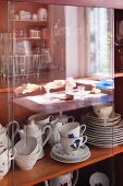 Traditional coffee services behind sliding glass doors of display cabinet