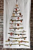 Stylised Christmas tree made from mossy branches with festive decorations hanging on white cloth