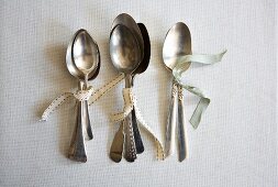 Various silver spoons tied together with ribbon
