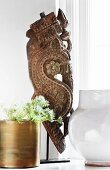 Antique, carved sculpture, plant in brass pot and ceramic vase on windowsill