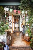 Cluttered vintage terrace decorated with fabric bunting and view into kitchen