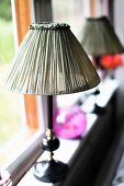 Antique table lamp with fabric lampshade on windowsill
