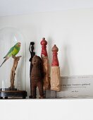 Vintage Menschenfigur und Holz Skulpturen in Miniaturform, neben geschlossenem Glasbehälter mit Papageien-Figur