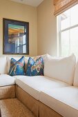 Zimmerecke mit Wandbild & Übereck-Sofagarnitur mit blauen Zierkissen