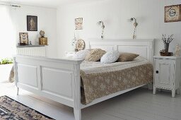 White, wooden double bed with bedside tables in vintage, country-house style
