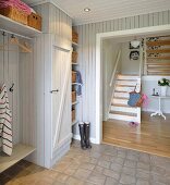 Wood-panelled hallway with integrated coat rack and dog-leg staircase in background