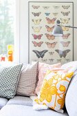 Retro scatter cushions on corner sofa and picture of butterflies in background