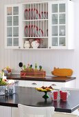 Red and white beakers on breakfast bar and plate rack integrated into wall cabinet