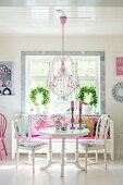 Pink chandelier above white dining set and bench below window