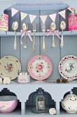 Silver cutlery and antique decorative plates on wooden shelves