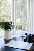Scandinavian ceramic pot of hydrangeas and candlestick on black surface in front of window