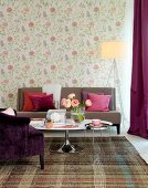 Tulip Couchtisch und hellbraune Couch vor Wand mit floraler Tapete in Pastelltönen, seitlich Stehleuchte