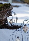 Baubles made from metal rings with silver Christmas baubles hanging from tree trunk in snowy landscape