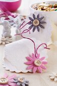 Selbstgemachte Täschchen aus Prägepapier für Ostersüssigkeiten dekoriert mit Filzblüten & Knöpfen