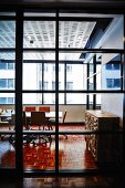 View through floor-to-ceiling, lattice window elements into meeting room with sunny facades beyond