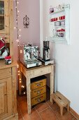 Coffee mill and espresso machine on rustic side table next to wall-mounted spice rack in corner of kitchen