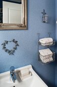 White towels in rack mounted on blue-painted bathroom wall