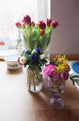 Bouquets in various glass vases on table