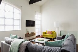 Loungebereich mit Eckcouch, gelbem Polstersessel und Stehlampe im Designerstil