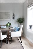 Classic theme; upholstered chairs with blue-pattered scatter cushions at dining table in renovated period apartment with stucco frieze