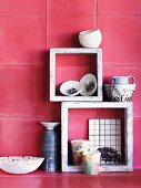 China and ceramic pots in and on stone frames against deep pink wall tiles
