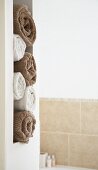 Gerollte Handtücher in Weiß und Braun in gemauerter Regalöffnung eines Bades