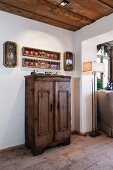 Objets d'art in framed glass cases on wall above old farmhouse cupboard in living area of restored chalet