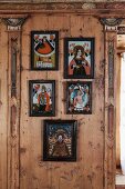 Framed religious folk art between pilasters on artistically wood-panelled wall