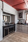 Large kitchen range in pale grey country-house kitchen with coffered ceiling