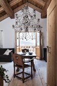 Silver chandelier sculpture above rustic seating area and view of Alpine landscape through open balcony doors