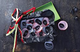 Selbstgebastelter Adventskalender aus kleinen Muffinförmchen und schwarzen Kieselsteinen