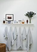 Helles Wandregal mit Badutensilien über aufgehängten, hellgrauen Handtüchern an Wand
