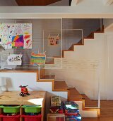 Wohnraumtreppe mit Kinderspielbereich und am schnurbespannten Geländer aufgehängte Kinderzeichnungen