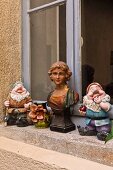 French garden gnomes and antique bust of woman on windowsill of historical building