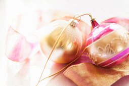 Golden- und pinkfarbene Weihnachtskugeln auf Geschenkband