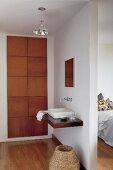 Washing area - washstand and wall-mounted taps on partition wall and fitted cupboard with solid wooden doors to one side