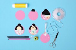Instructions for hand-crafting Japanese Kokeshi pendants using various papers, ribbon and pattern punch